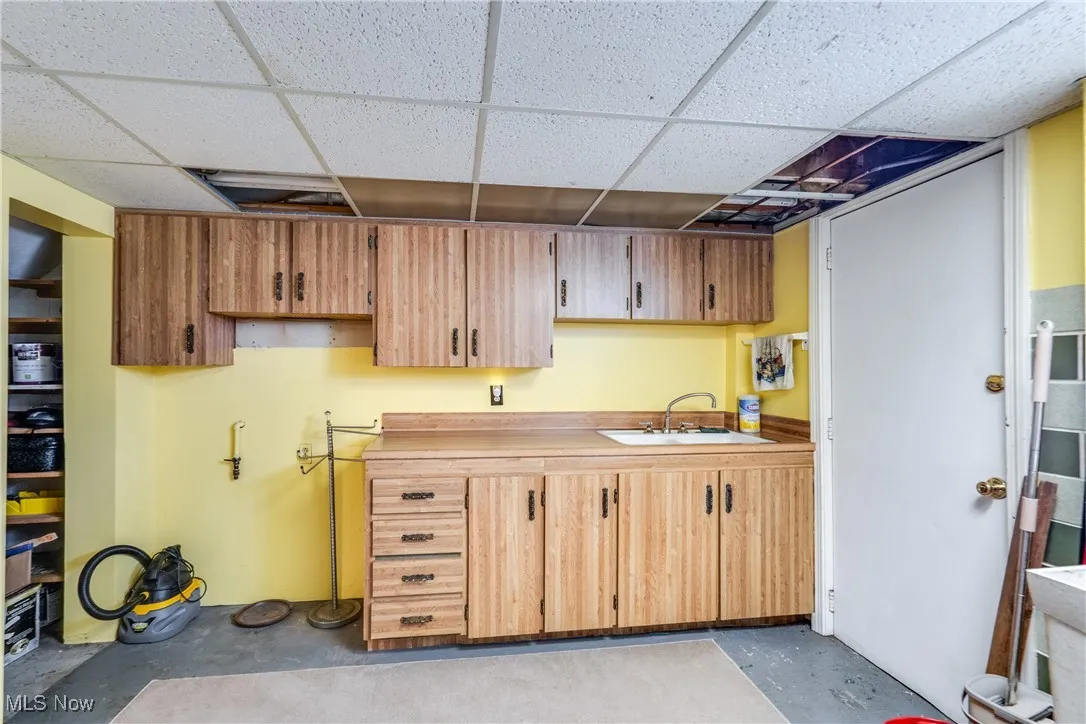 Kitchen featuring unfinished concrete flooring, a drop ceiling, and light countertops