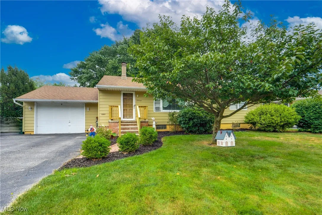 View of front facade featuring an attached garage, asphalt driveway, a front yard, and a shingled roof