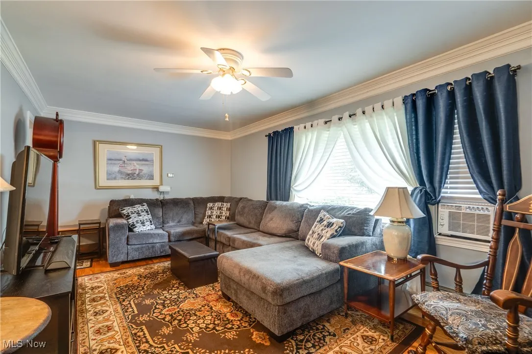 Living room featuring a ceiling fan, ornamental molding, and wood finished floors