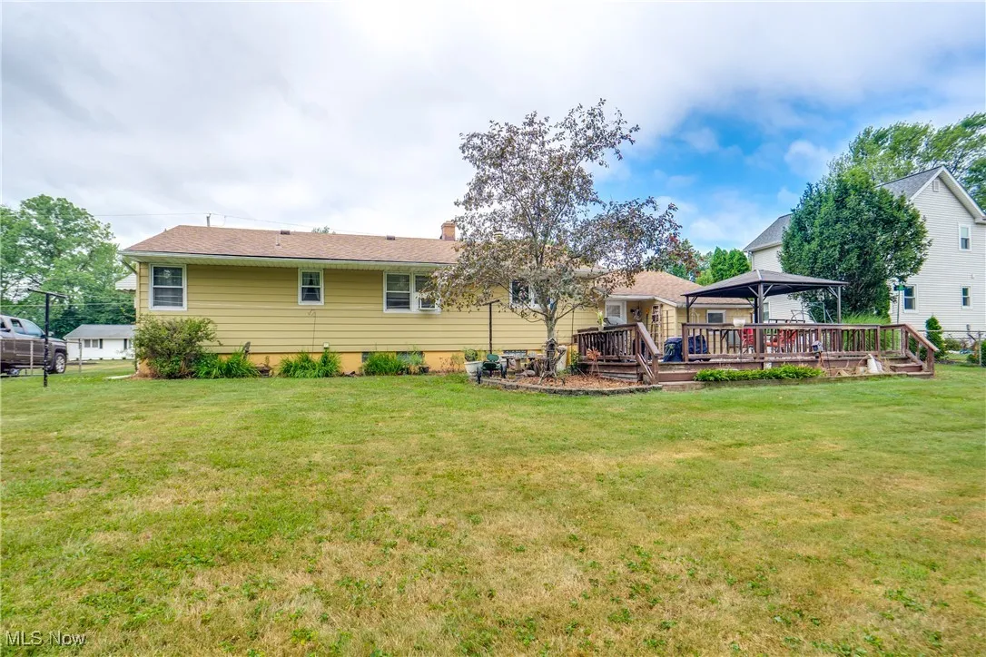 Rear view of property featuring a gazebo, a lawn, a wooden deck, and a chimney