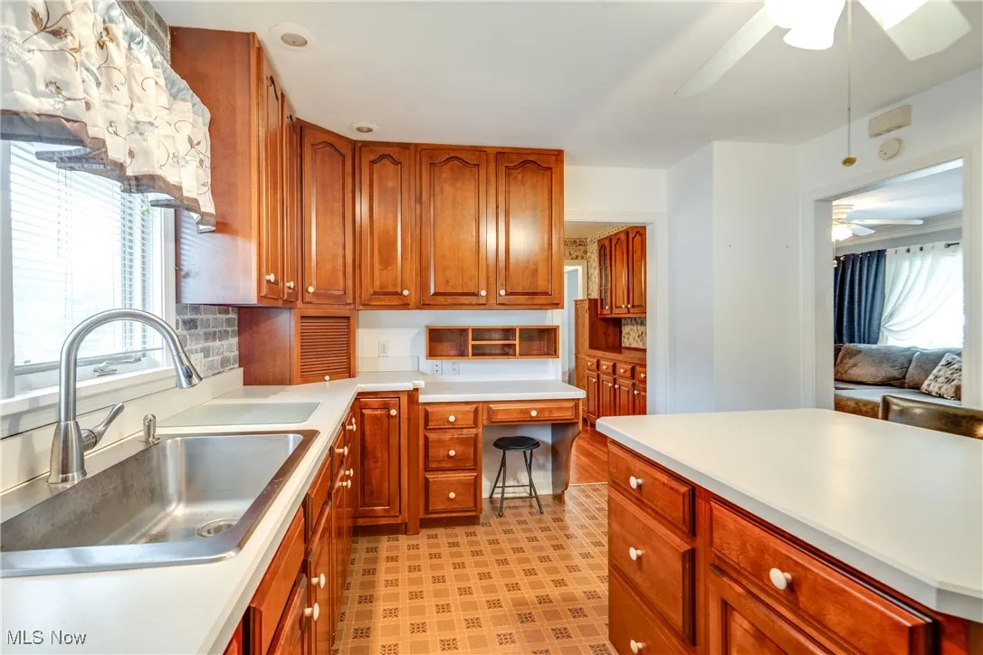 Kitchen featuring ceiling fan, light countertops, light floors, brown cabinets, and tasteful backsplash