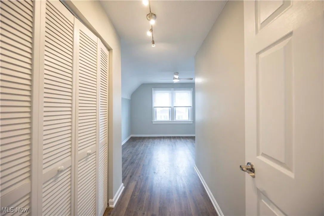 Hallway with dark wood-style floors and vaulted ceiling