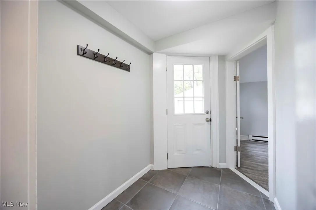 Doorway to outside with tile patterned flooring and a baseboard heating unit