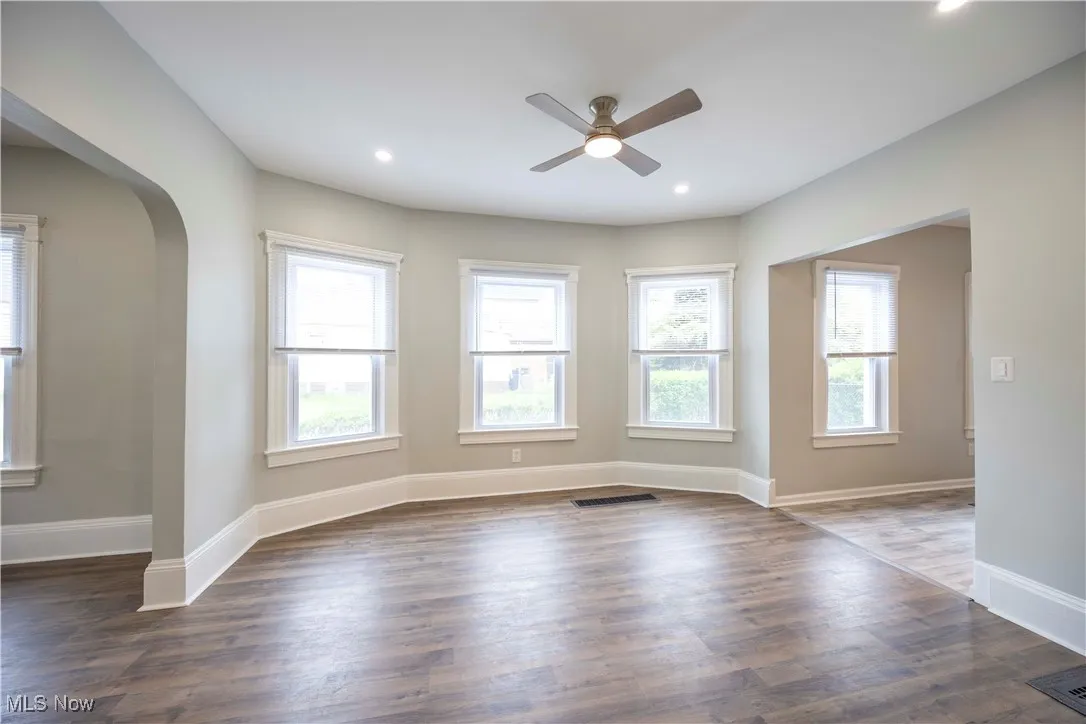 Spare room featuring ceiling fan, plenty of natural light, arched walkways, dark wood-style flooring, and recessed lighting
