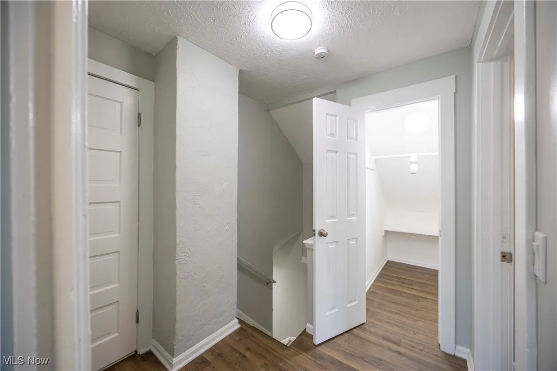 Corridor featuring wood finished floors, an upstairs landing, and a textured ceiling