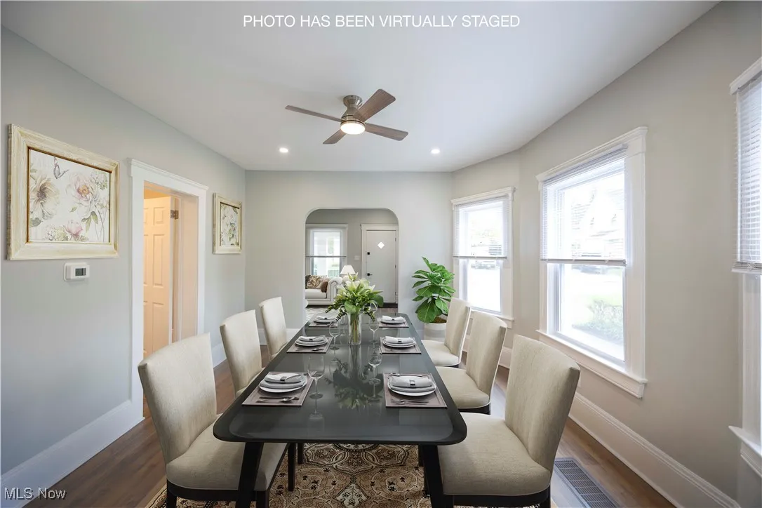 Dining room with arched walkways, a ceiling fan, dark wood-type flooring, and recessed lighting