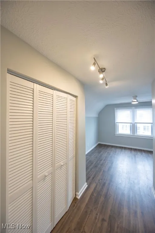 Bonus room featuring a textured ceiling, dark wood-type flooring, and lofted ceiling