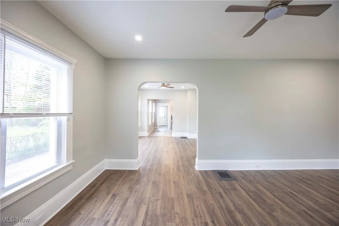 Spare room featuring a ceiling fan, arched walkways, dark wood-style floors, and recessed lighting