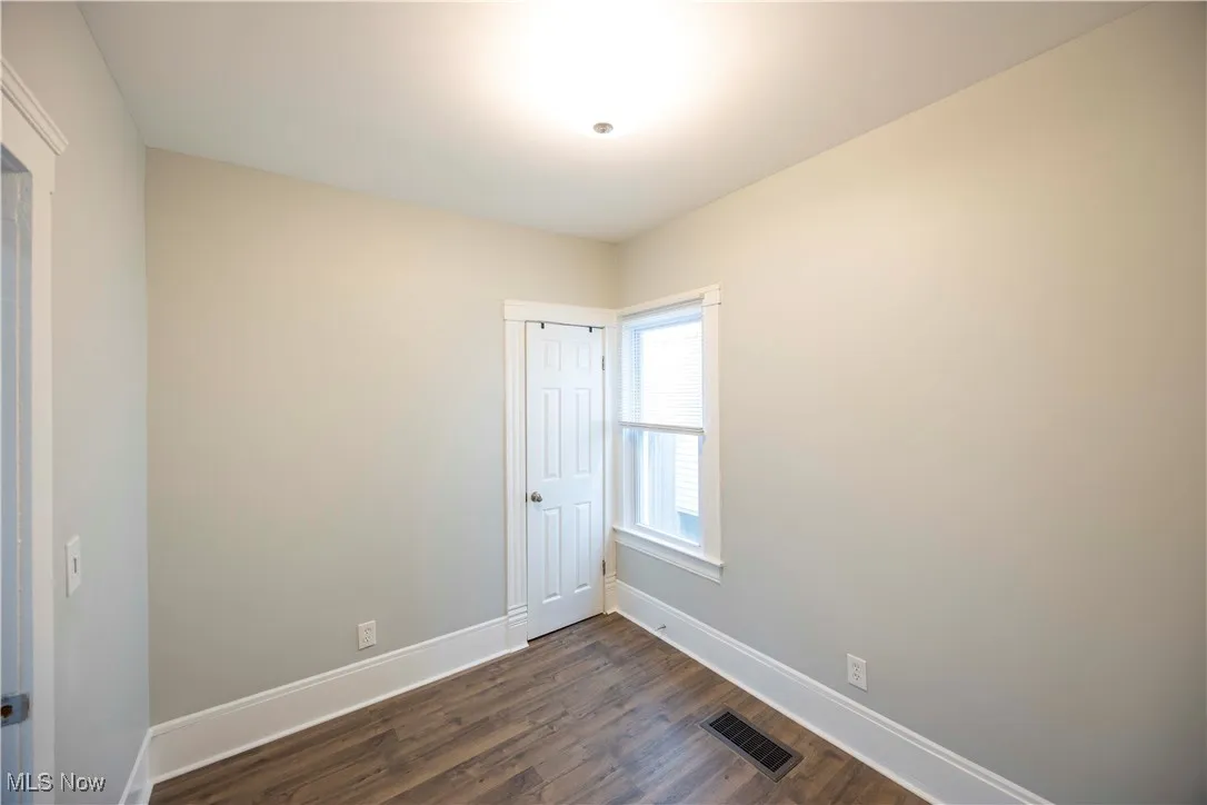 Unfurnished room featuring dark wood-type flooring and baseboards