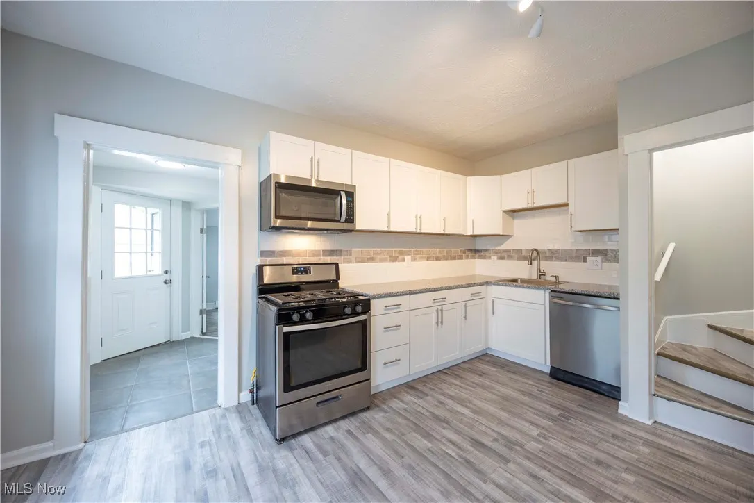 Kitchen with appliances with stainless steel finishes, white cabinetry, and light wood-type flooring