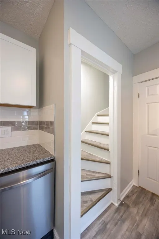 Stairs featuring wood finished floors and a textured ceiling