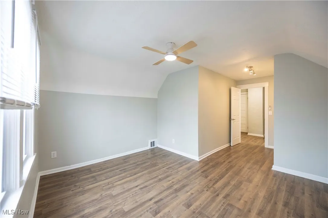 Bonus room with lofted ceiling, a ceiling fan, and dark wood-style flooring
