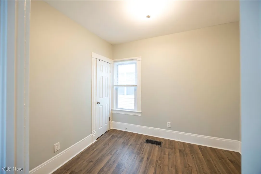 Empty room featuring baseboards and dark wood finished floors