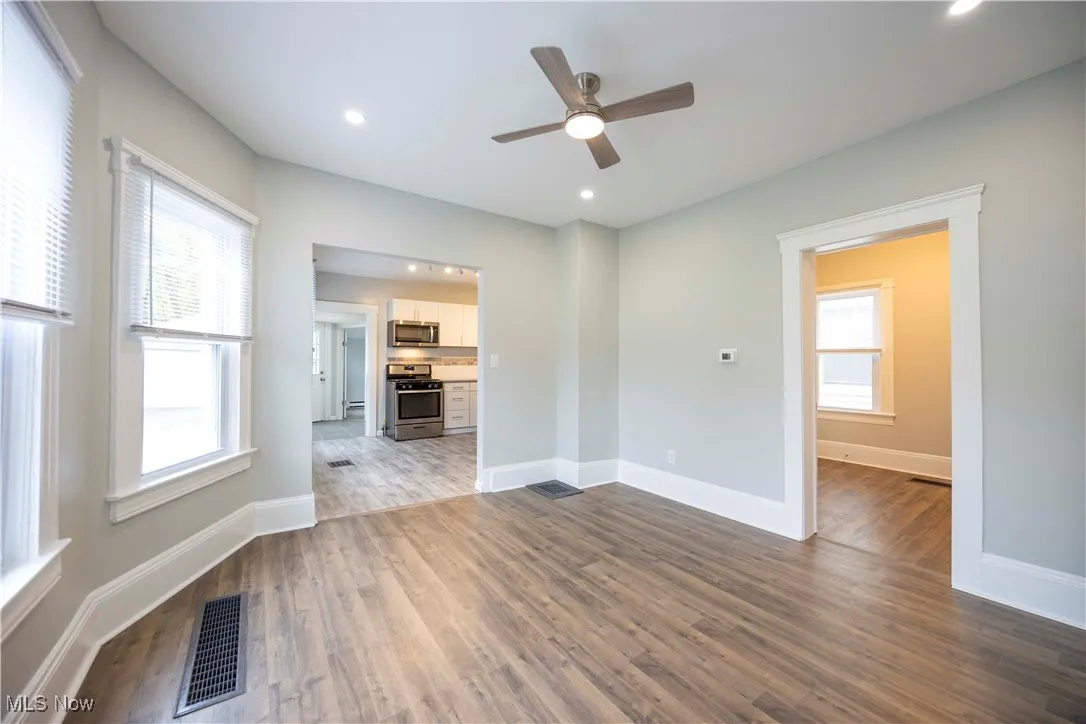 Unfurnished living room featuring healthy amount of natural light, a ceiling fan, dark wood-style flooring, and recessed lighting
