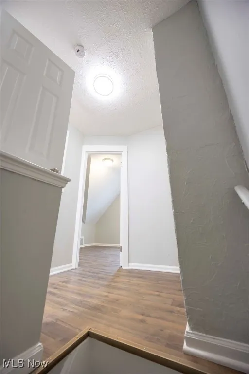 Hallway featuring wood finished floors and a textured ceiling