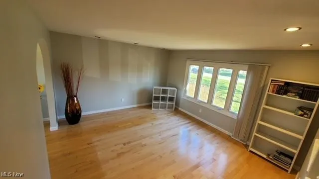 Spare room with wood finished floors, recessed lighting, and arched walkways