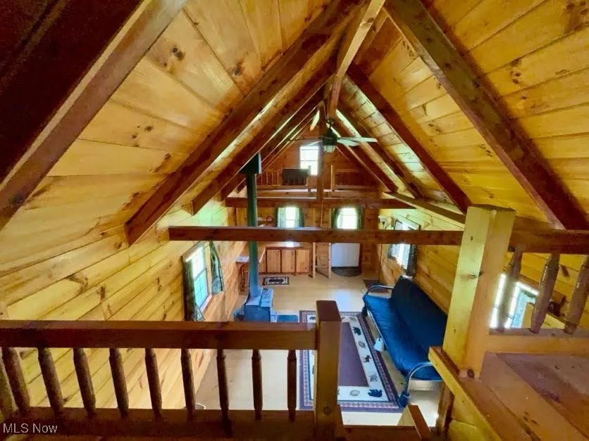 Bonus room featuring wooden ceiling, wooden walls, and ceiling fan