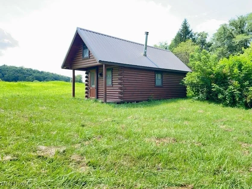 View of property exterior with log exterior and a metal roof