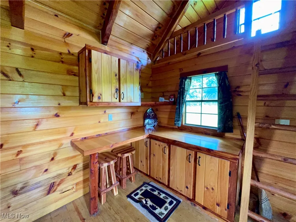 Kitchen with wooden ceiling, wood walls, light countertops, and light wood-style floors