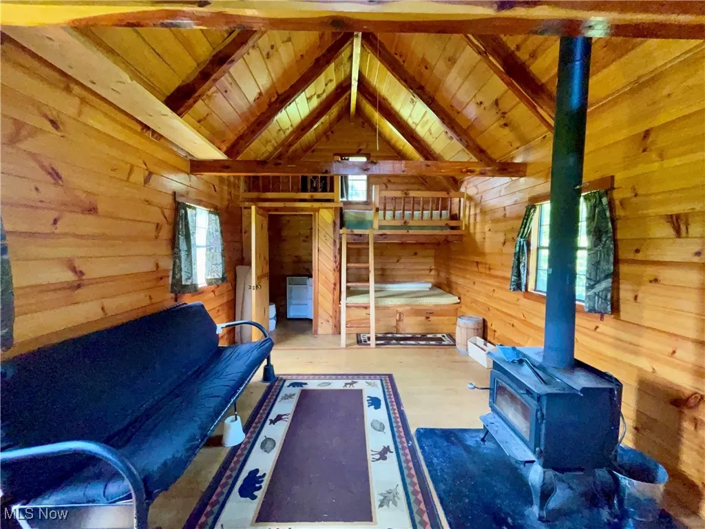 Bedroom featuring wooden ceiling, a wood stove, wooden walls, and wood finished floors