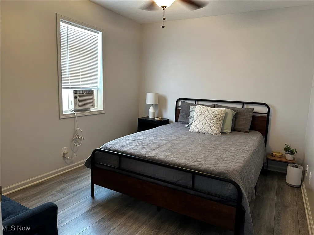 Bedroom featuring wood finished floors, multiple windows, and a ceiling fan