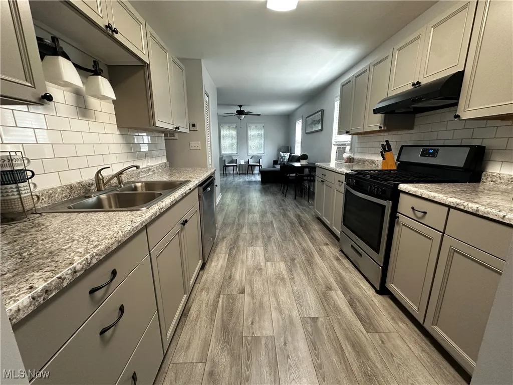 Kitchen featuring stainless steel appliances, gray cabinetry, light wood-style flooring, under cabinet range hood, and ceiling fan