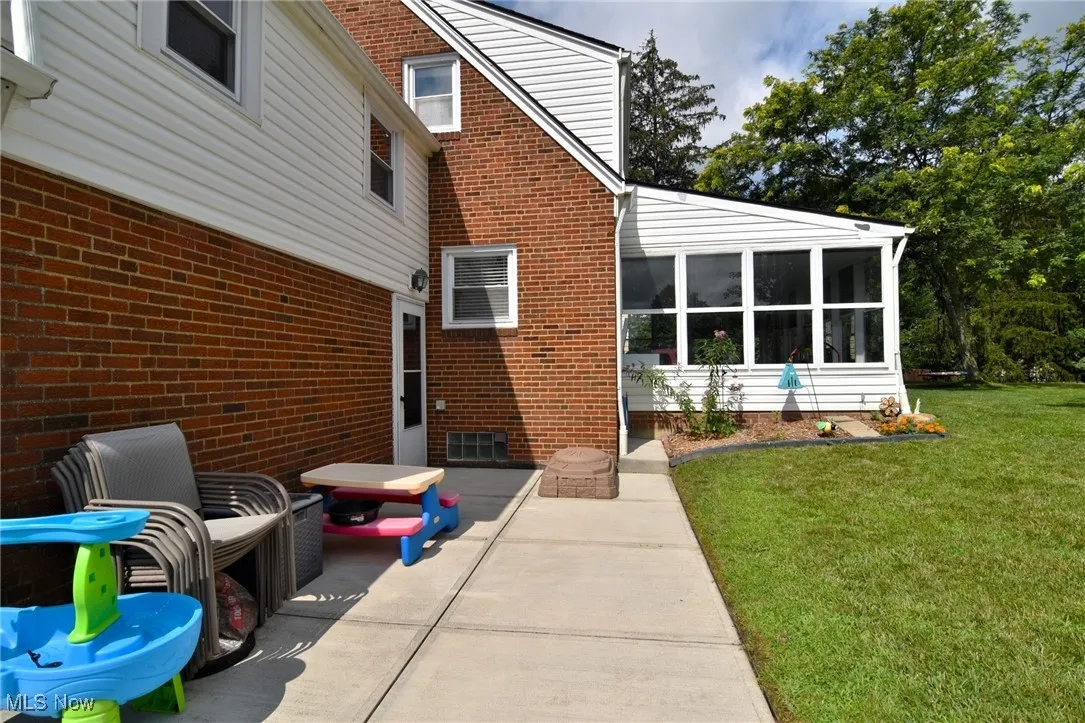 Concrete patio area with view of sunroom.