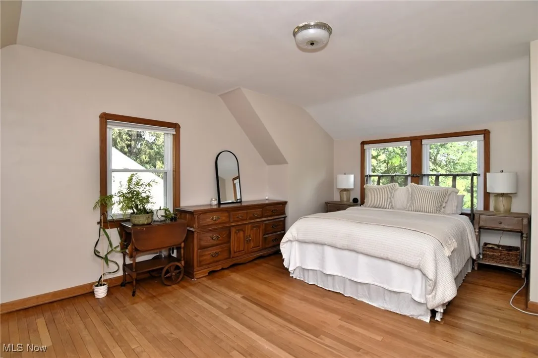 Bedroom with light wood-style flooring, lofted ceiling, and multiple windows