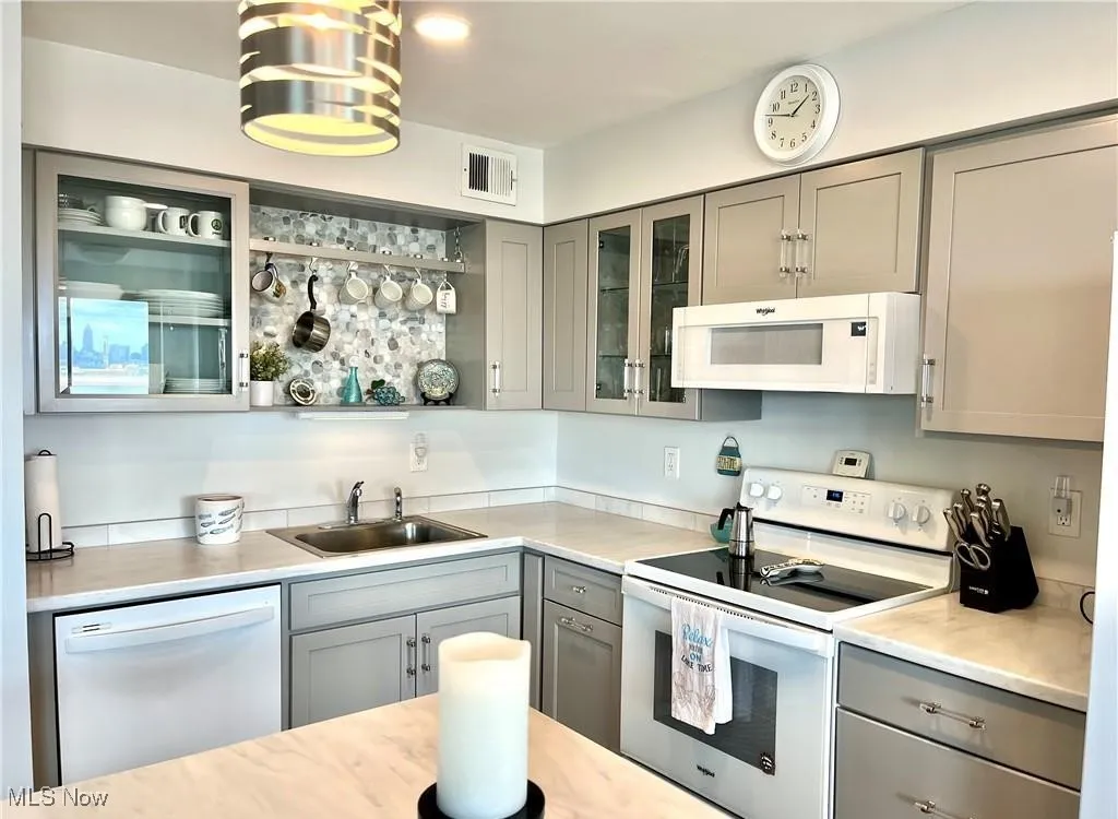 Kitchen featuring gray cabinetry, white appliances, light countertops, and glass insert cabinets