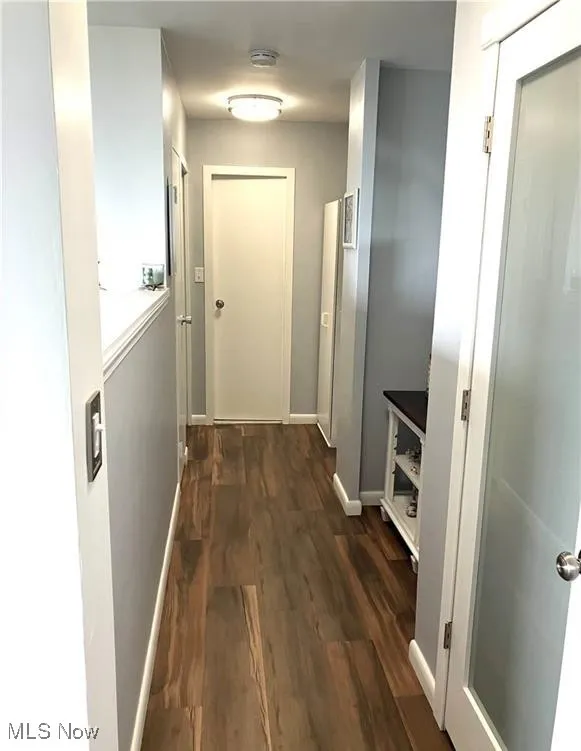 Hallway featuring baseboards and dark wood-style floors