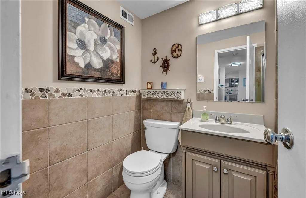 Bathroom featuring tile walls, vanity, and wainscoting