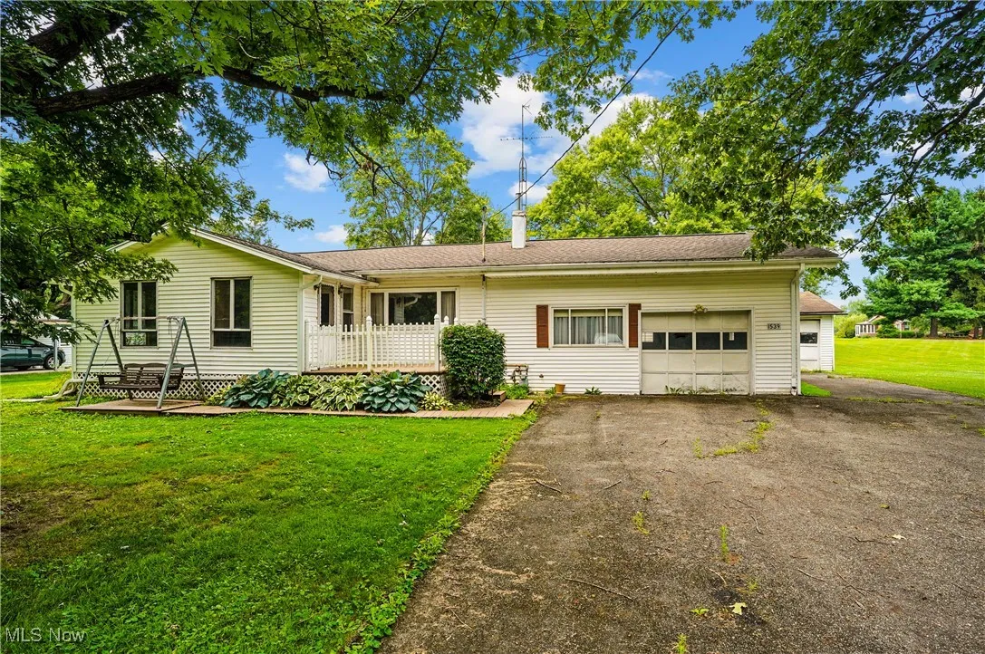 Ranch-style home with an attached garage, asphalt driveway, a front lawn, and a chimney