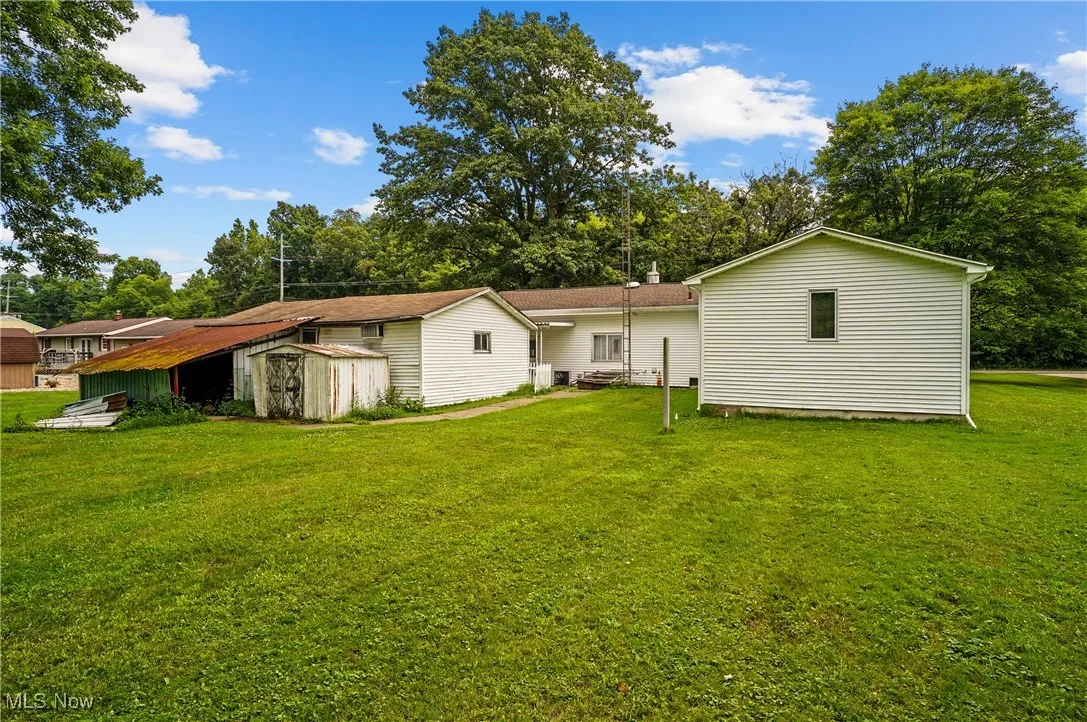 Back of property with a storage unit and a lawn