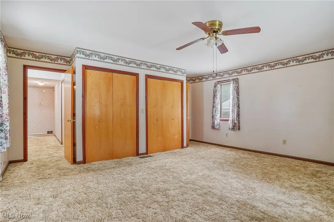 Unfurnished bedroom featuring carpet flooring, multiple closets, and ceiling fan
