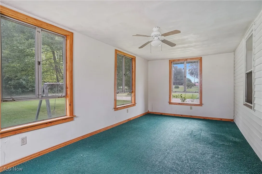 Carpeted spare room featuring a ceiling fan and baseboards