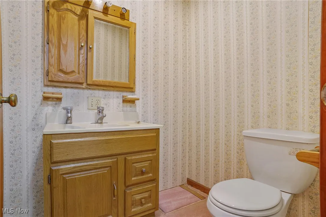 Bathroom with vanity and wallpapered walls