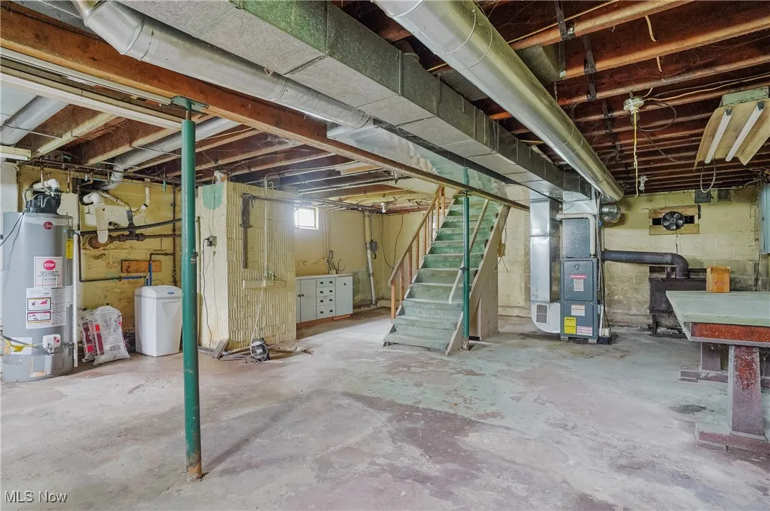 Below grade area featuring gas water heater, stairway, and heating unit