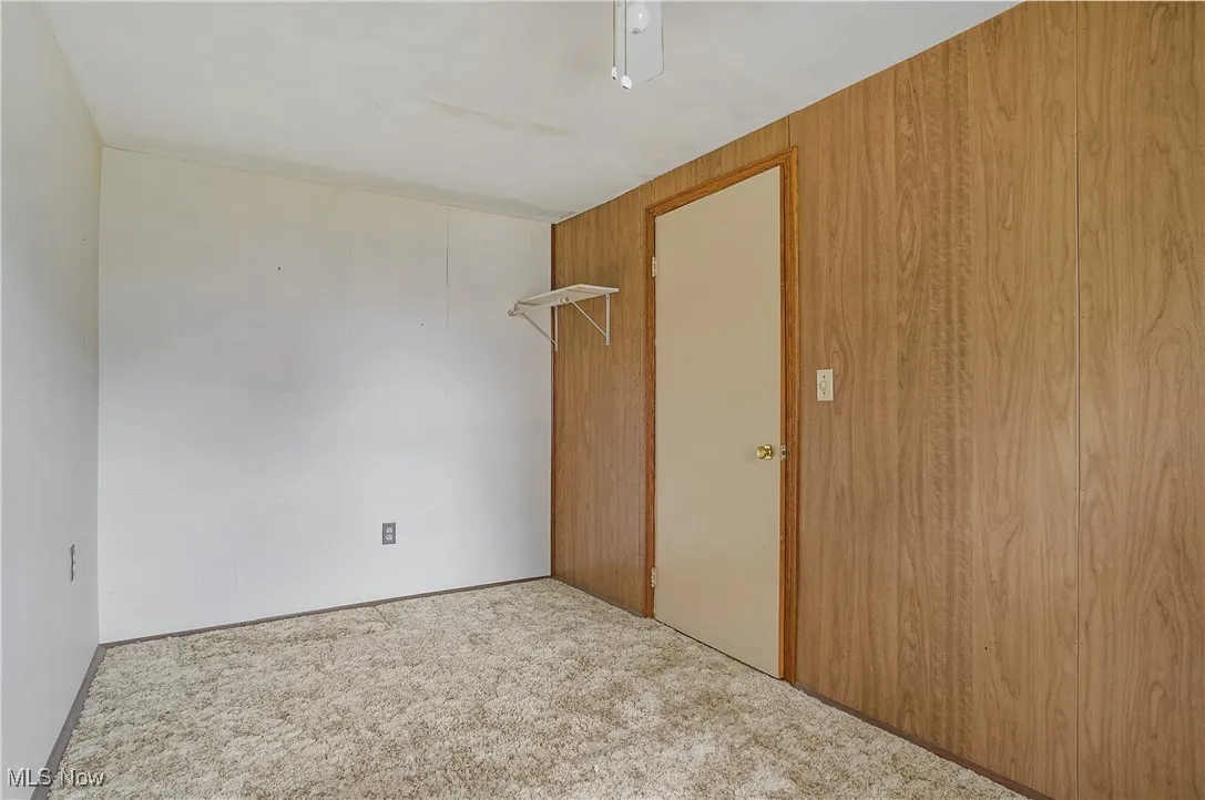 Unfurnished room featuring carpet floors and wooden walls