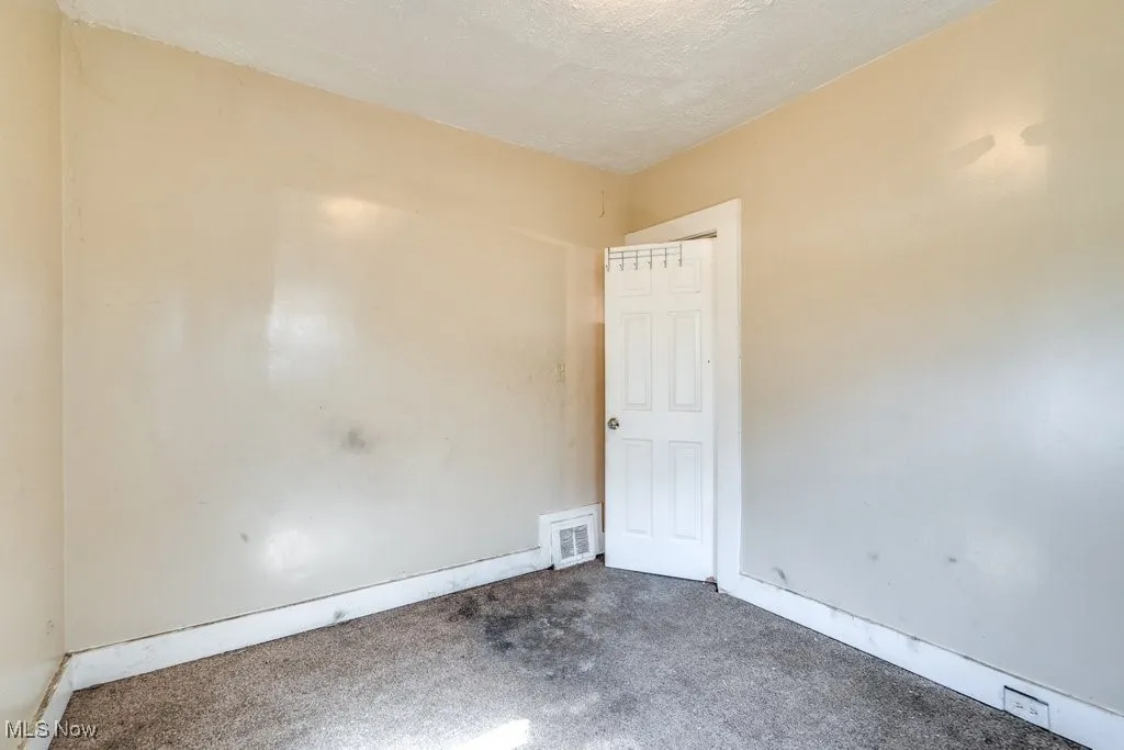 Carpeted spare room featuring baseboards
