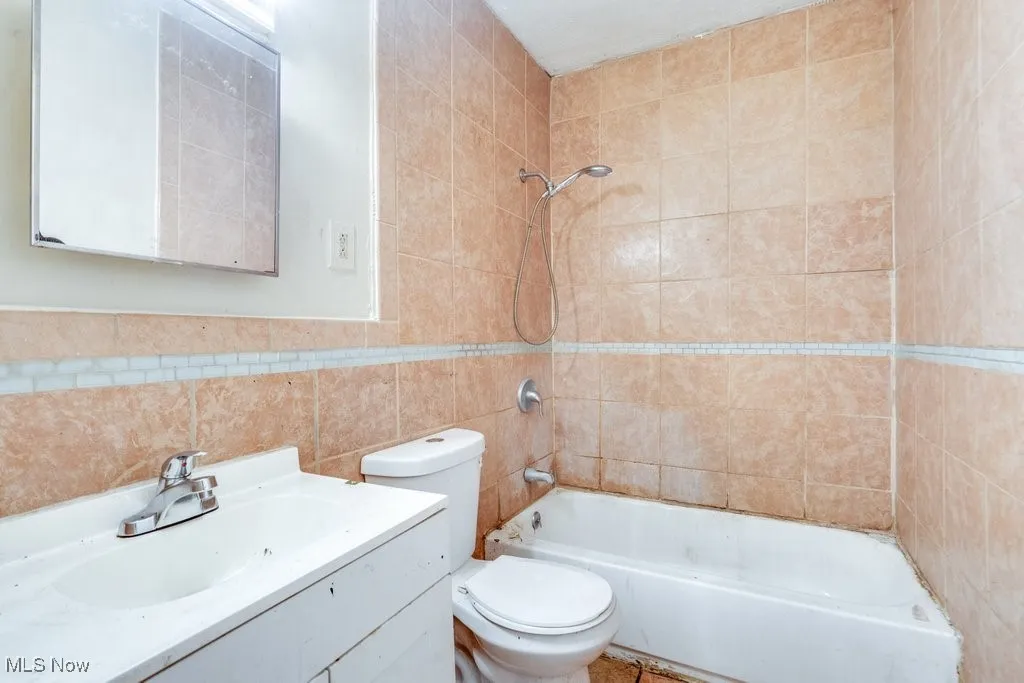 Bathroom featuring bathing tub / shower combination, vanity, and tile walls