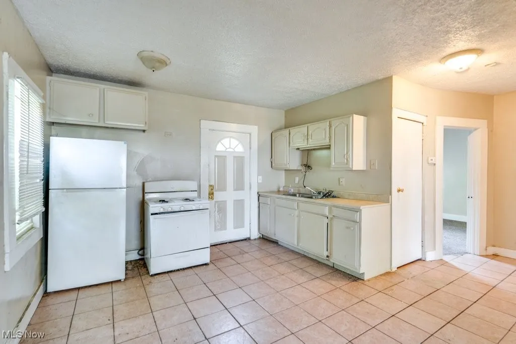 Kitchen featuring white appliances, healthy amount of natural light, light countertops, a textured ceiling, and light tile patterned floors