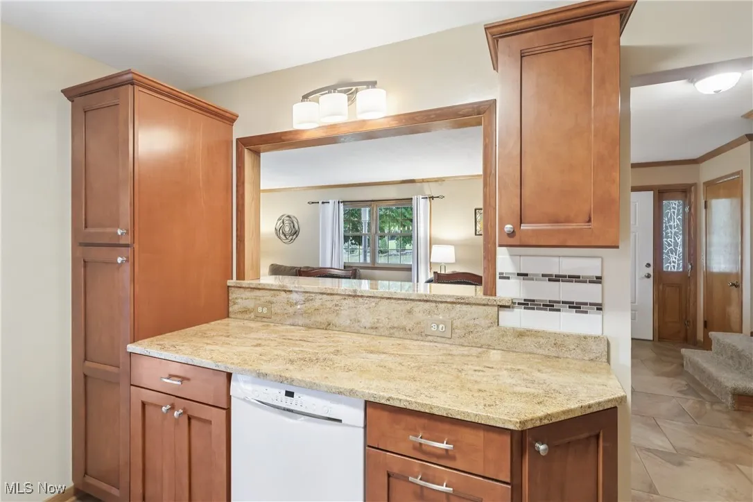 Kitchen with white dishwasher, granite counterops and cupboards