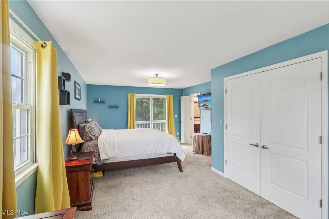 Primary bedroom with a balcony, double closet and carpet flooring