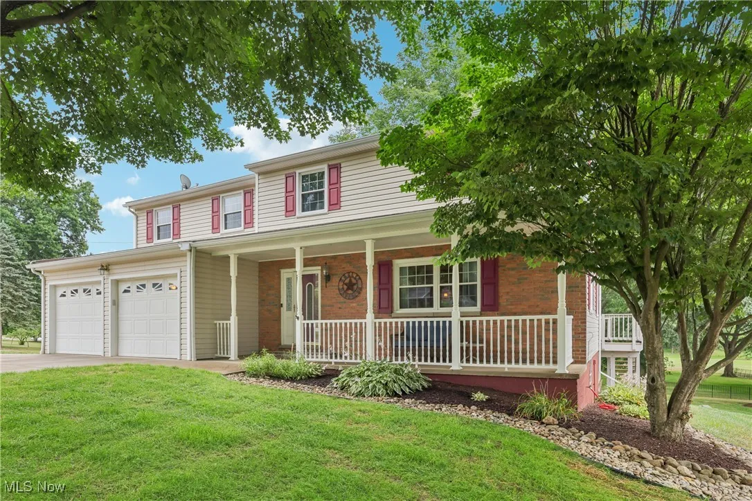 Front / side of the home with a covered porch, 2 car detached garage and large yard