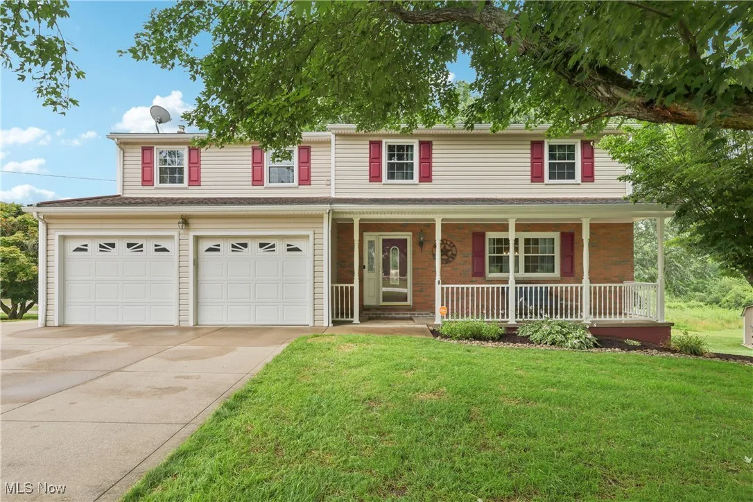 Front of home with a covered porch, 2 car attached garage and large front yard