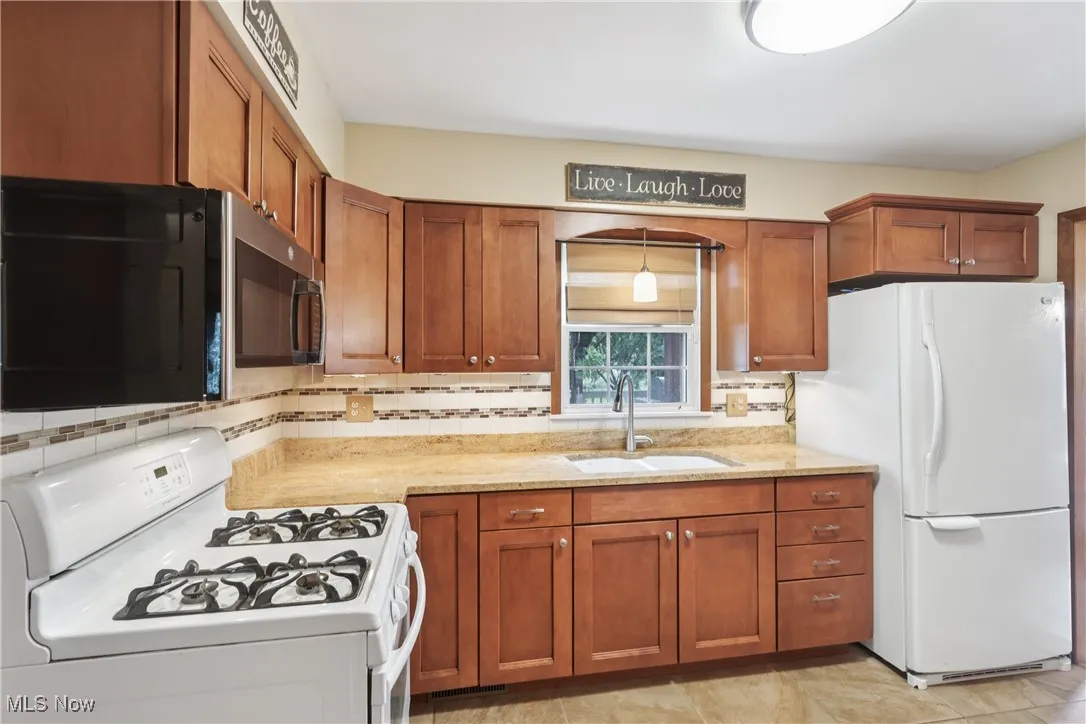 Kitchen featuring white appliances, sink, Granite countertops, cupboards, and a tasteful backsplash