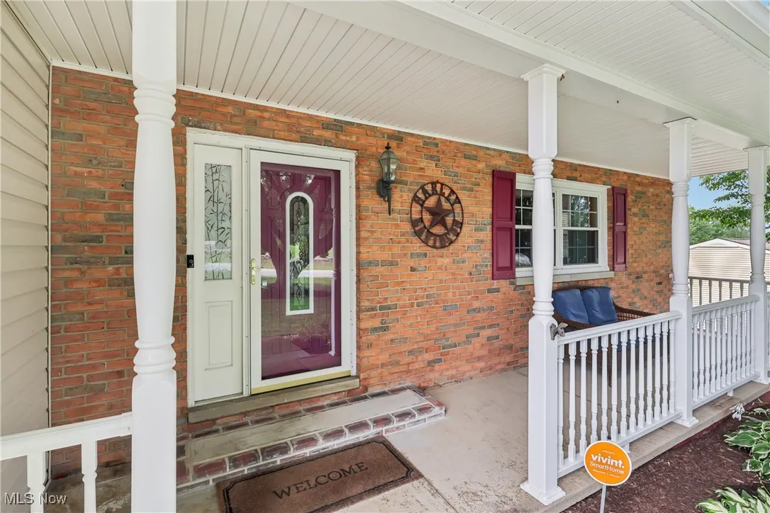 View of exterior entry featuring brick siding and covered porch