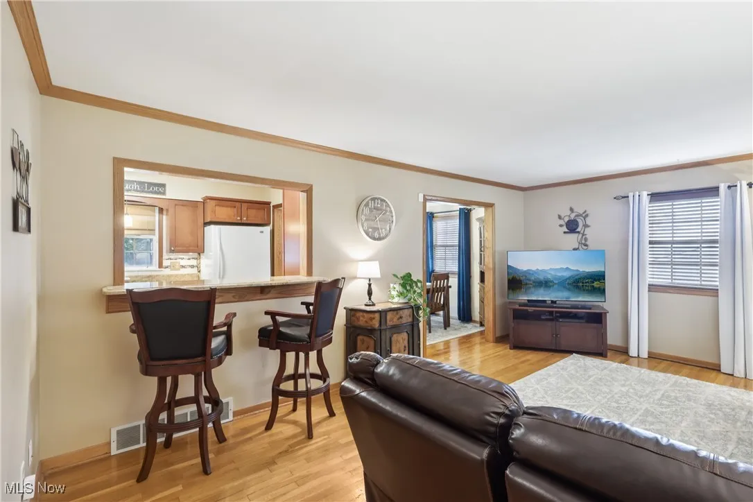 Living room features a breakfast bar with Granite countertop and wood flooring