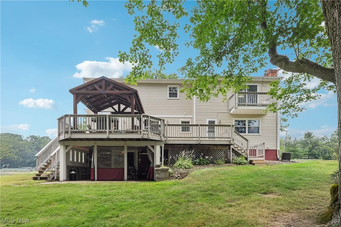 Rear view of home with a deck and heated 4 season / sun room
