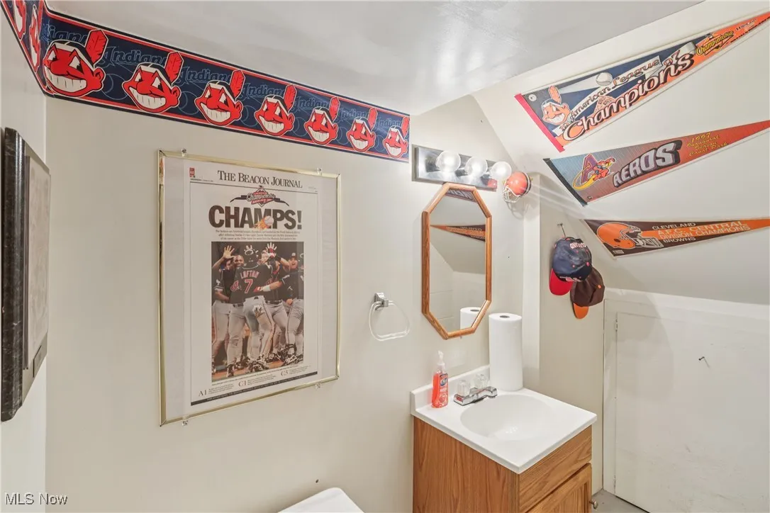 Lower level half bathroom featuring sink, vanity and commode